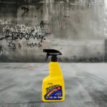 Tricleanium Graffiti Remover 750mL in action on graffiti-covered surface, showing a clean result.