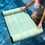 Woman positioning the AcquaBoss Mint Green water hammock in a swimming pool.