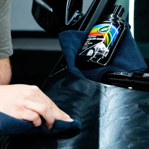 Person buffing Turtle Wax Color Magic Jet Black Wax FG52708 500ml on a black car with a microfiber cloth after hazing.