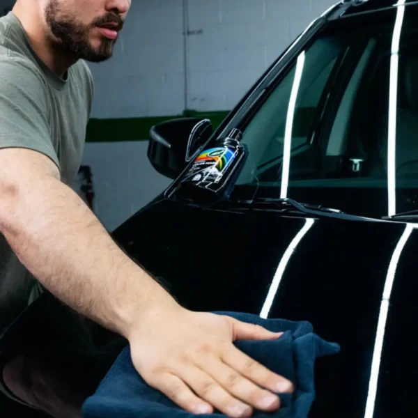 Buffing off Turtle Wax Color Magic Jet Black Wax FG52708 500ml from a black car with a microfiber