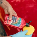 Turtle Wax Color Magic Radiant Red Wax FG52711 500ml next to a red car bonnet, showing polish application on white background