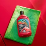 Front view of Turtle Wax Color Magic Radiant Red Wax FG52711 500ml bottle on green and red background