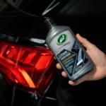 Turtle Wax Hybrid Solutions Black Polish 414ml placed beside a clean black car panel mid-polish on white background